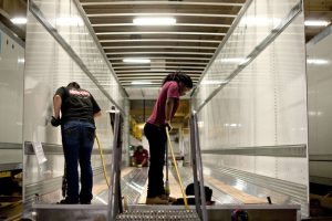 Workers drill holes to secure flooring to the frame of a semi trailer at the Wabash National Corp. facility in Lafayette Indiana, Fleets refurbish older trailers, new trailer mfg can't keep up with demand